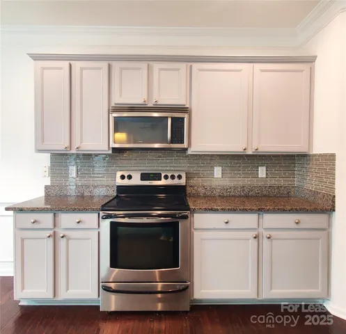 a kitchen with granite countertop white cabinets appliances and a sink