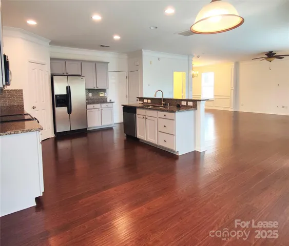 a large kitchen with a center island wooden floor stainless steel appliances and windows