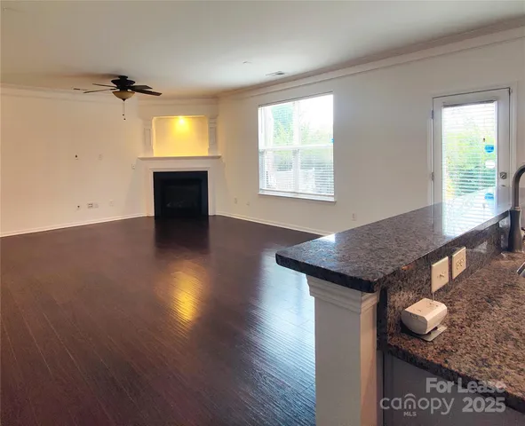 an empty room with wooden floor a fireplace and windows