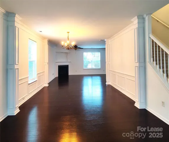 an empty room with wooden floor fireplace and windows