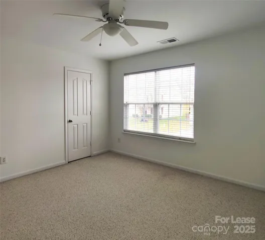 an empty room with windows and fan