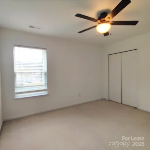 an empty room with a window and a fan