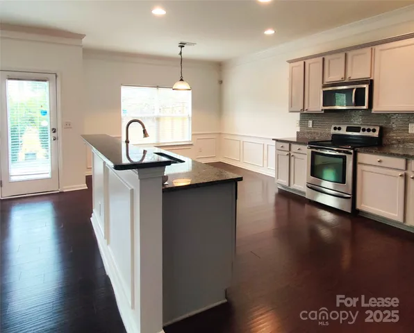 a kitchen with kitchen island granite countertop a stove and a wooden floor