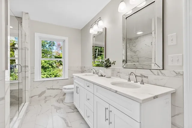 a bathroom with a double vanity sink toilet and a mirror