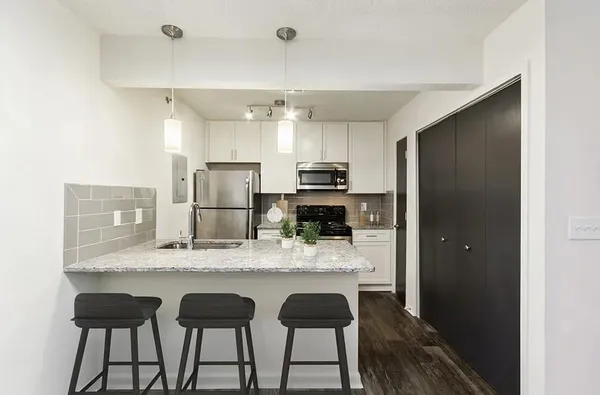 a kitchen with kitchen island granite countertop a table chairs refrigerator and microwave