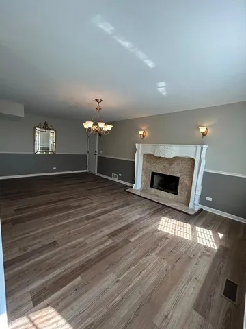 a view of a livingroom with a fireplace a chandelier and wooden floor
