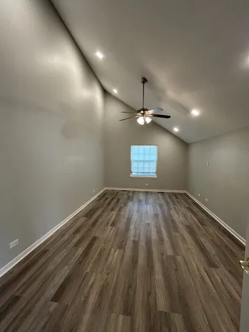 an empty room with wooden floor windows and ceiling fan