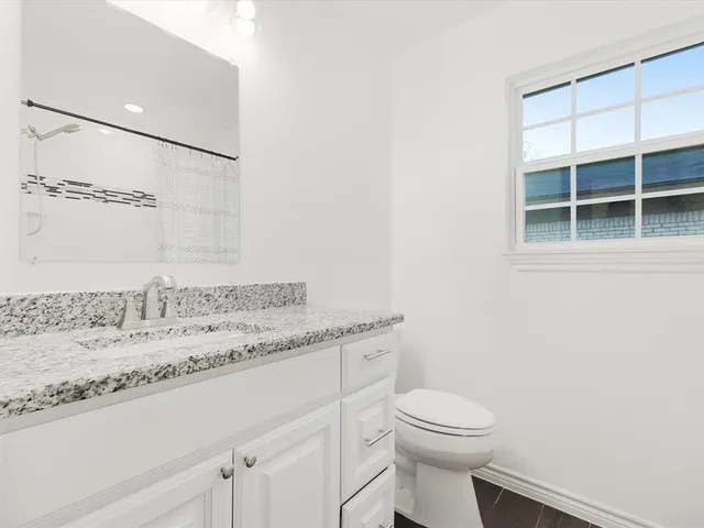 a bathroom with a granite countertop sink a toilet and a mirror