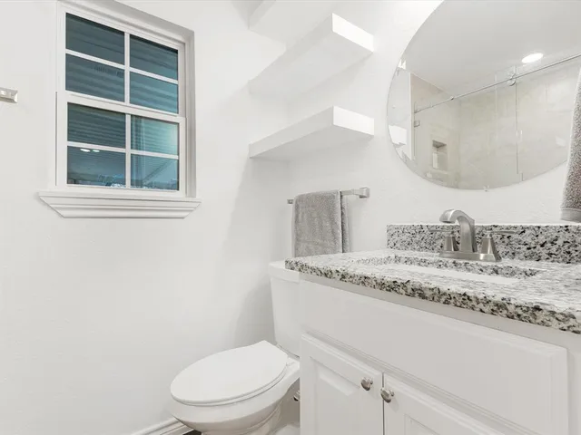 a bathroom with a granite countertop sink mirror vanity and toilet