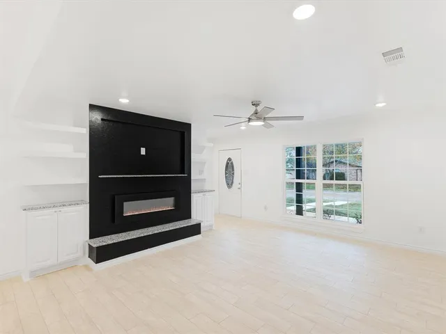 an empty room with windows and fireplace