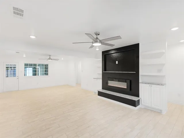 an empty room with a ceiling fan and a fireplace