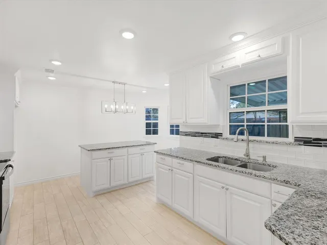 a kitchen with granite countertop a sink and white cabinets