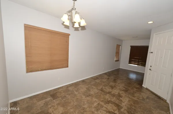 an empty room with chandelier fan and windows