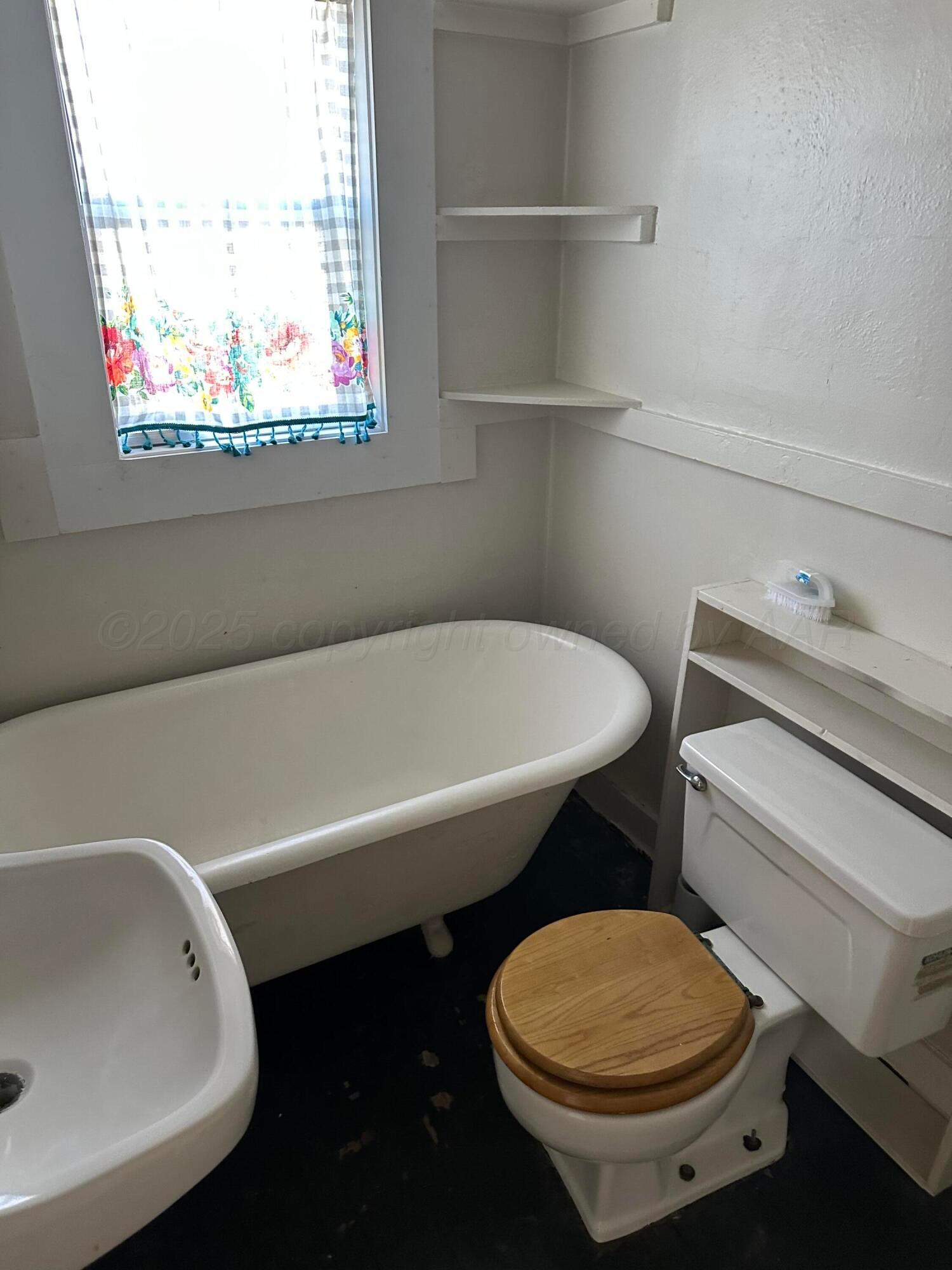 1021 Jackson Street Borger, TX 79007 - Photo 10 of 26 a bathroom with a toilet a sink and a bathtub