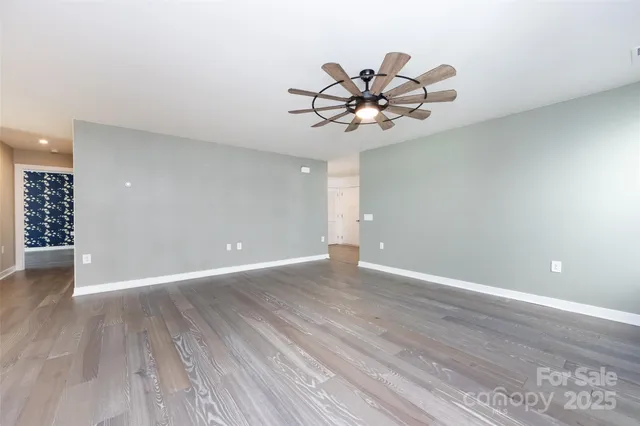 a view of an empty room with wooden floor and window