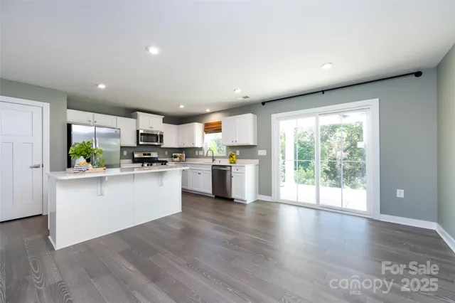 a kitchen with white cabinets and wooden floor