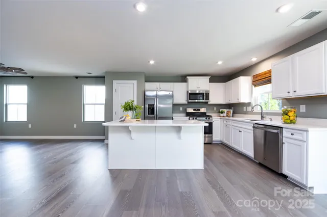 a kitchen with white cabinets stainless steel appliances a sink and a window