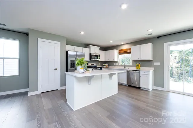 a kitchen with white cabinets and wooden floor