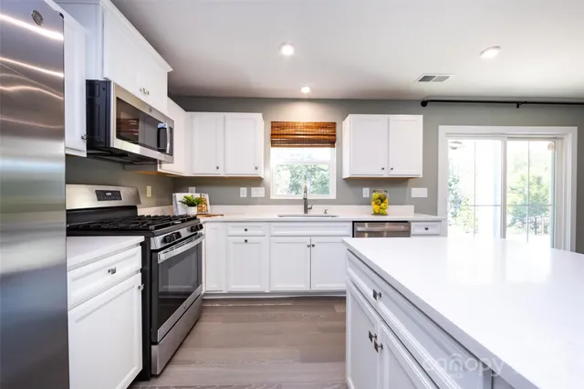 a kitchen with stainless steel appliances granite countertop a stove a sink and a microwave