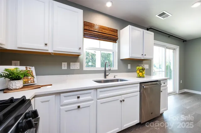 a kitchen with stainless steel appliances white cabinets and a window