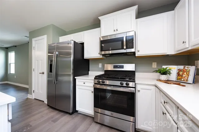 a kitchen with stainless steel appliances white cabinets a sink and a stove