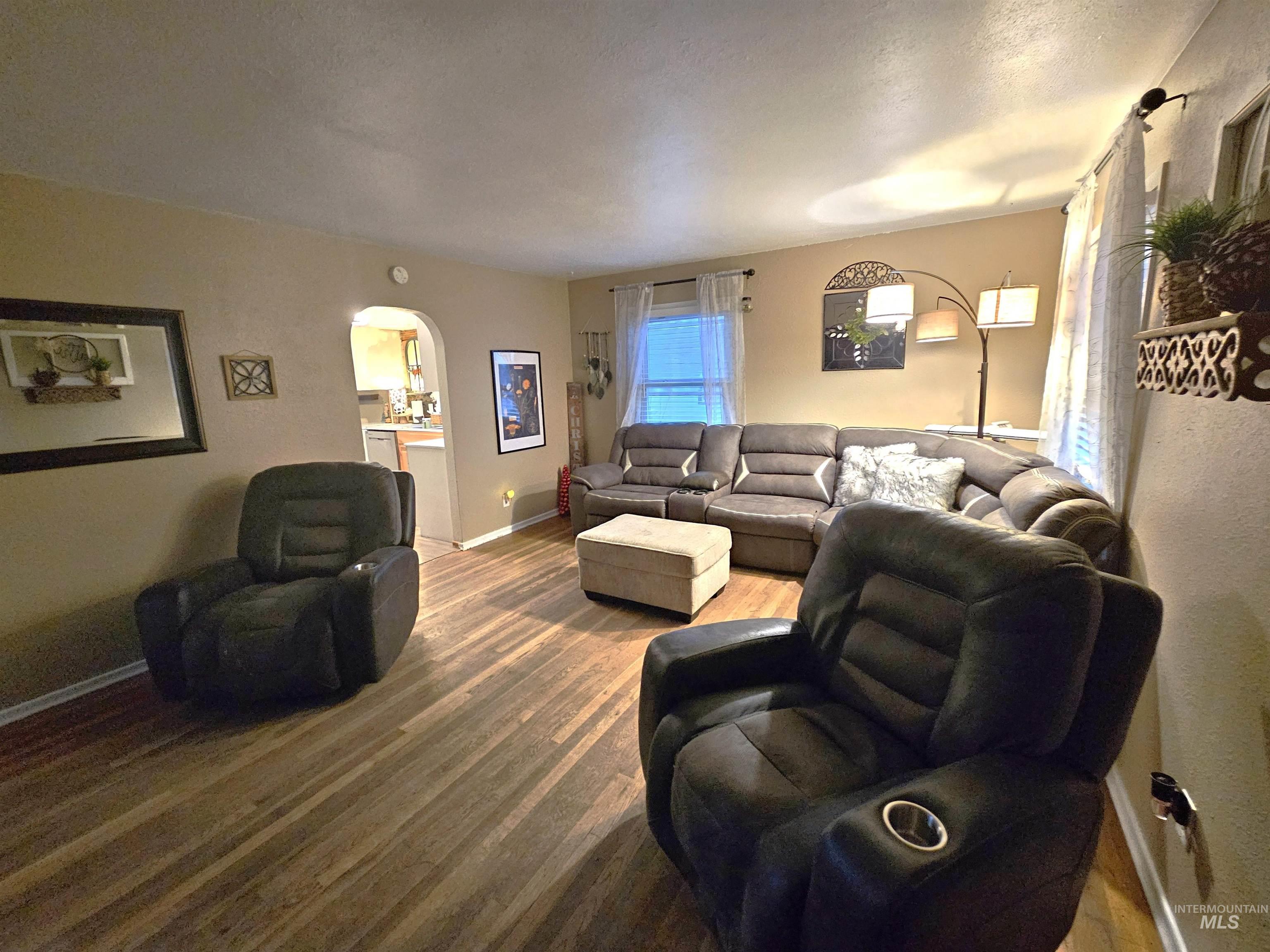 616 12th Street Clarkston, WA 99403 - Photo 2 of 24 Living room featuring arched walkways, a textured ceiling, and wood finished floors