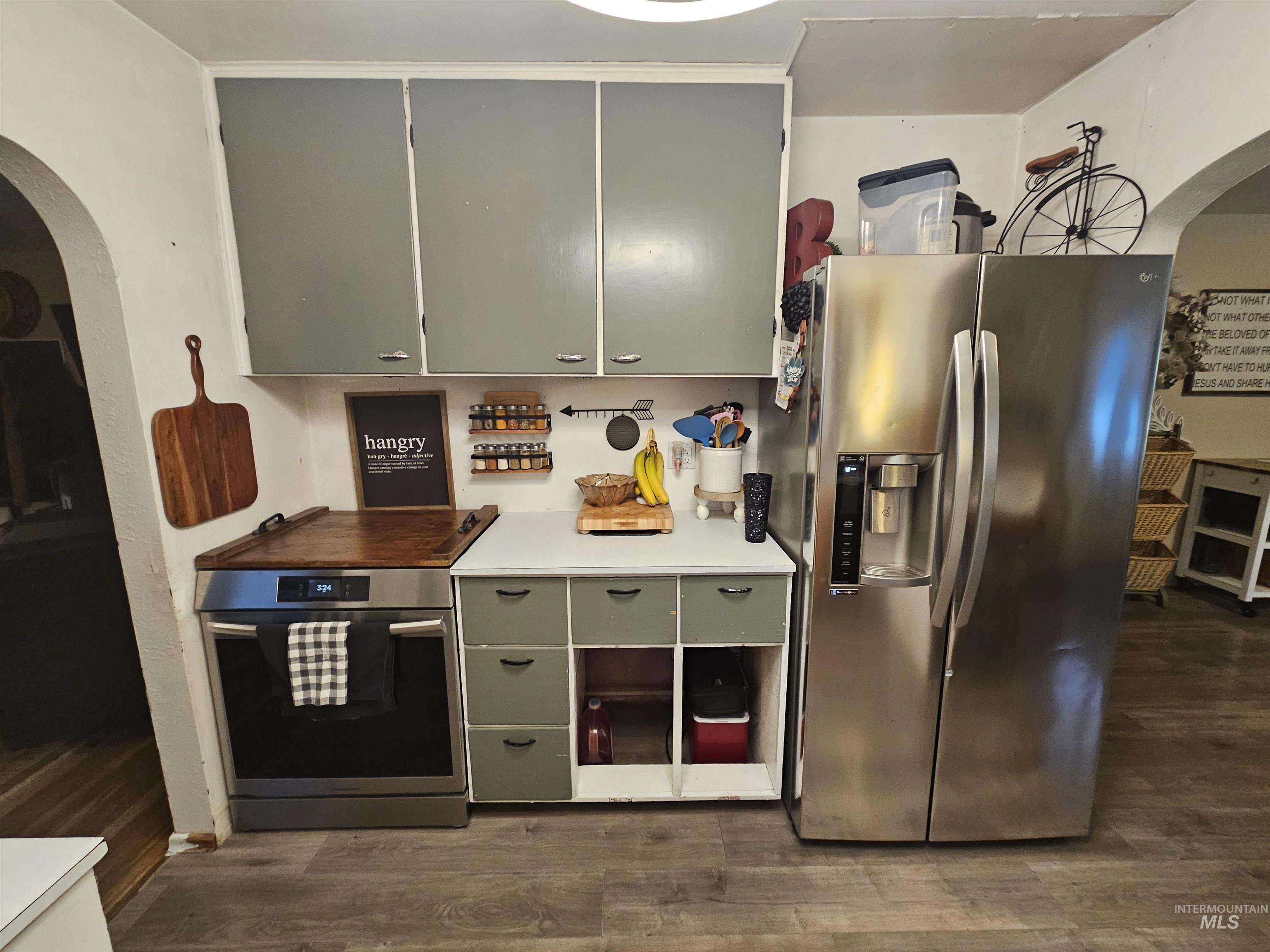 616 12th Street Clarkston, WA 99403 - Photo 5 of 24 Kitchen with arched walkways, stainless steel appliances, light countertops, dark wood-style floors, and green cabinets