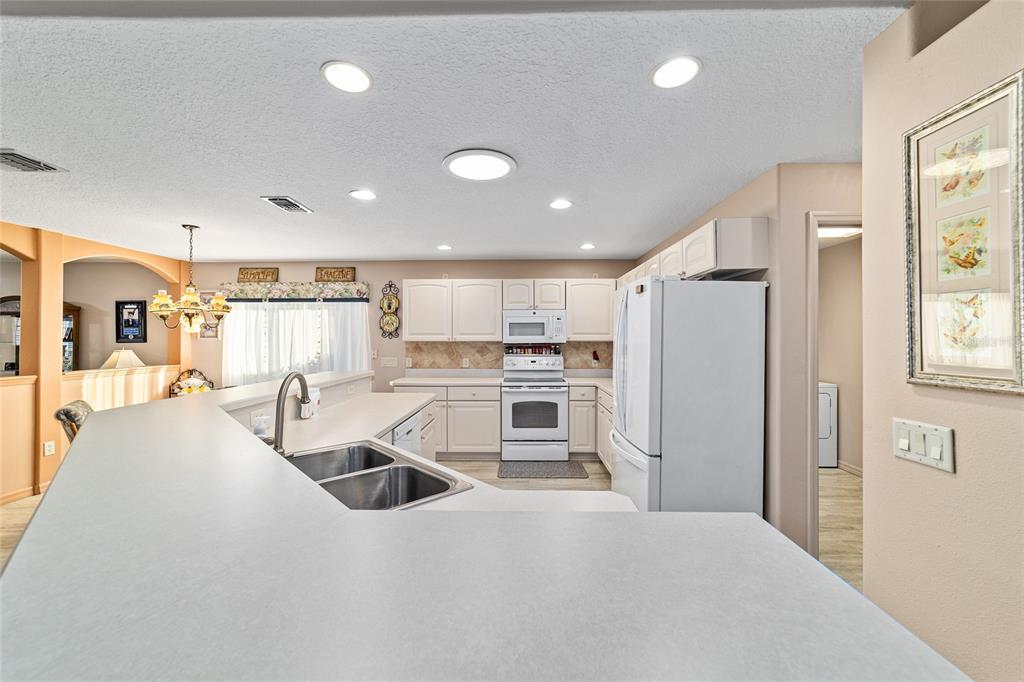15680 Southwest 13th Circle Ocala, FL 34473 - Photo 32 of 75 a large white kitchen with a stove a refrigerator a sink dishwasher with a dining table and chairs with wooden floor