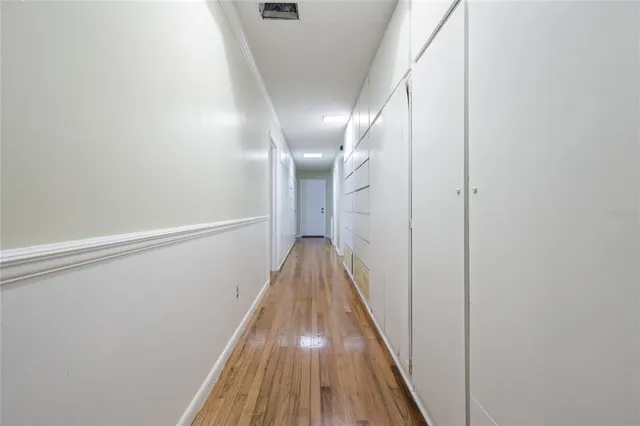 a view of empty room with wooden floor and fan