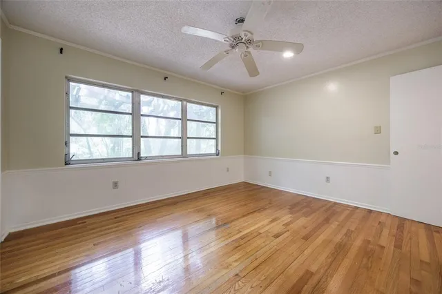 wooden floor in an empty room with a chandelier fan