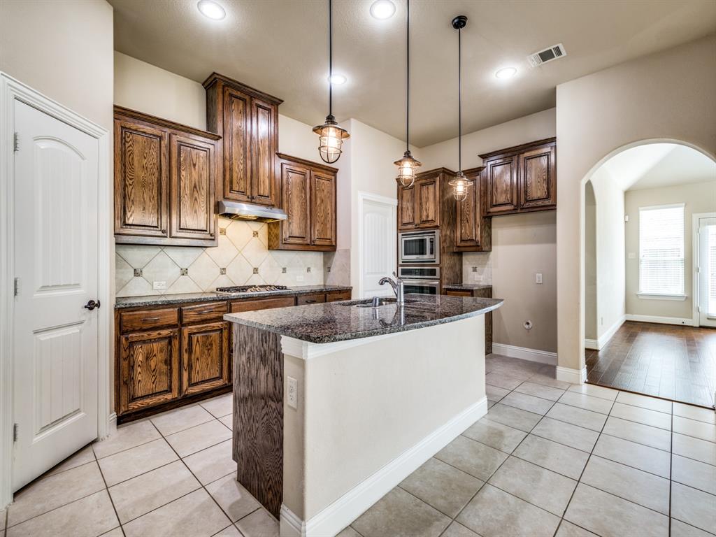 820 Callcott Street McKinney, TX 75072 - Photo 9 of 22 a kitchen with a sink a refrigerator and wooden cabinets