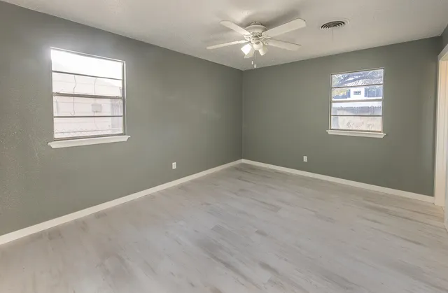 an empty room with wooden floor and windows