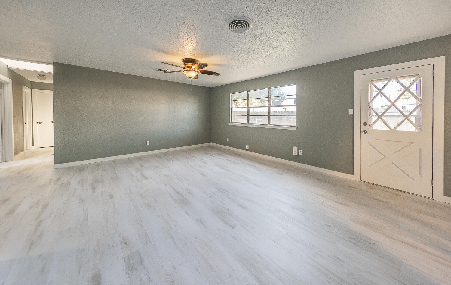 5405 49th Street Lubbock, TX 79414 - Photo 2 of 25 an empty room with wooden floor chandelier fan and windows