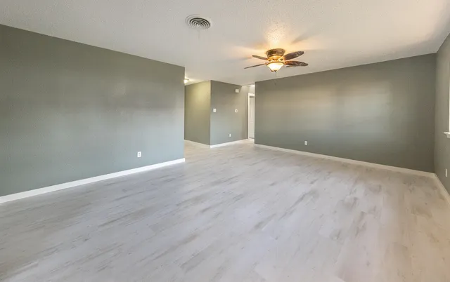 wooden floor in an empty room with a chandelier fan
