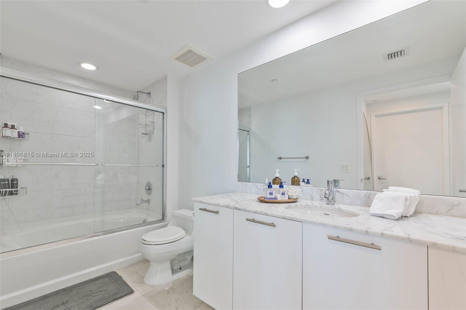 951 Brickell Avenue, Unit 1606 Miami, FL 33131 - Photo 17 of 30 a bathroom with a granite countertop sink mirror toilet and bathtub