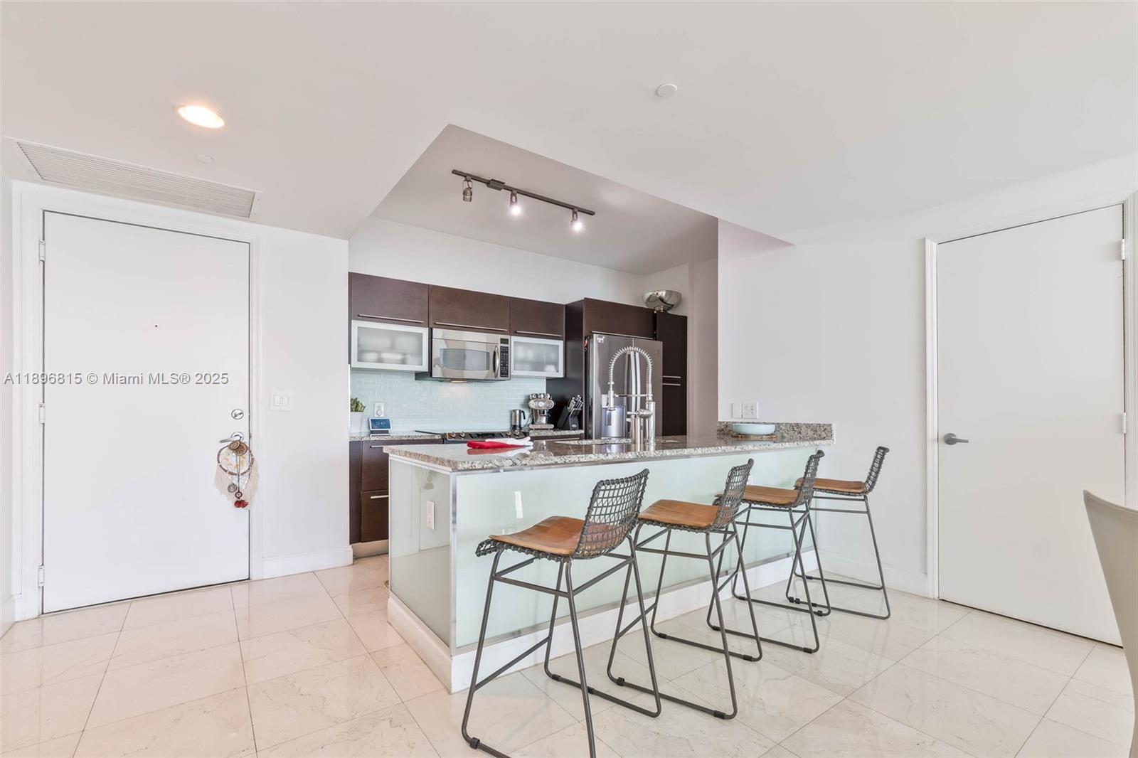 951 Brickell Avenue, Unit 1606 Miami, FL 33131 - Photo 18 of 30 a kitchen with a dining table chairs and refrigerator