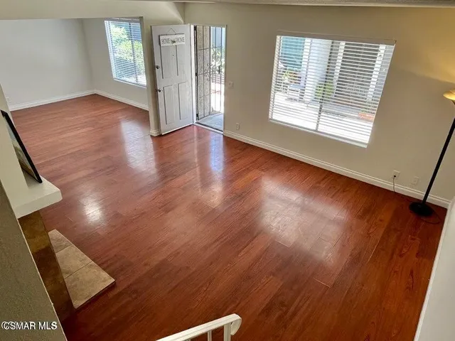 a view of an empty room with wooden floor and a window