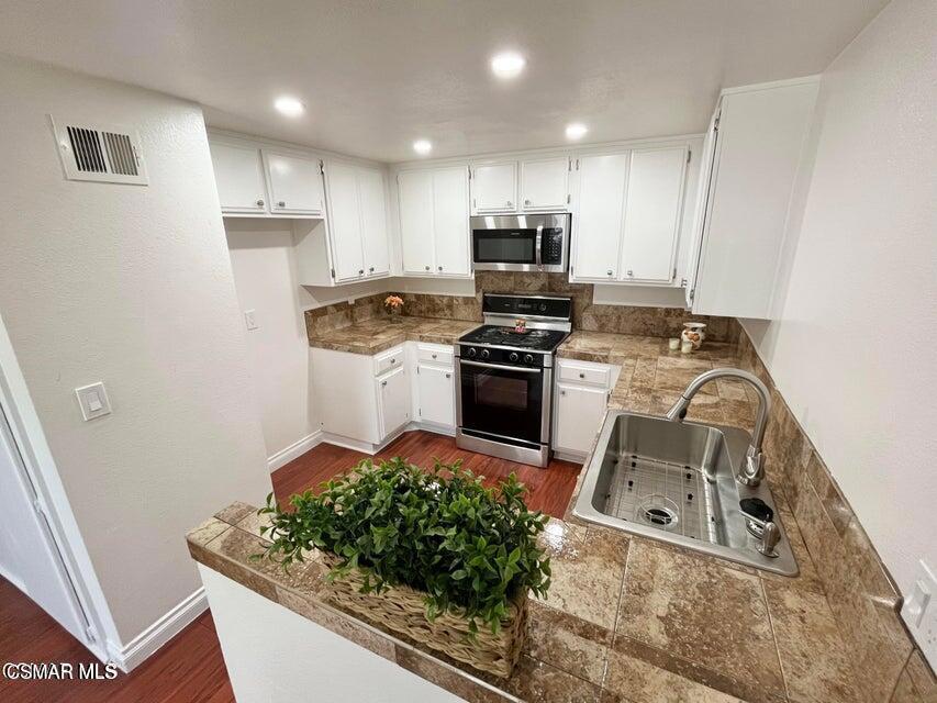 540 Spring Road, Unit 94 Moorpark, CA 93021 - Photo 7 of 22 a kitchen with stainless steel appliances granite countertop a stove top oven a sink a refrigerator and white cabinets