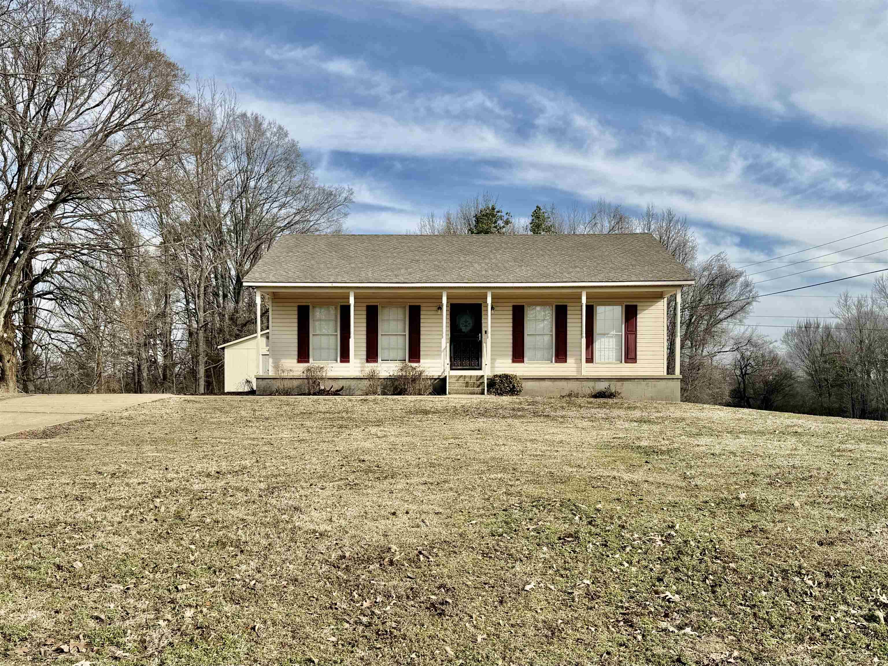Single story home with a porch, a shingled roof, and a front yard