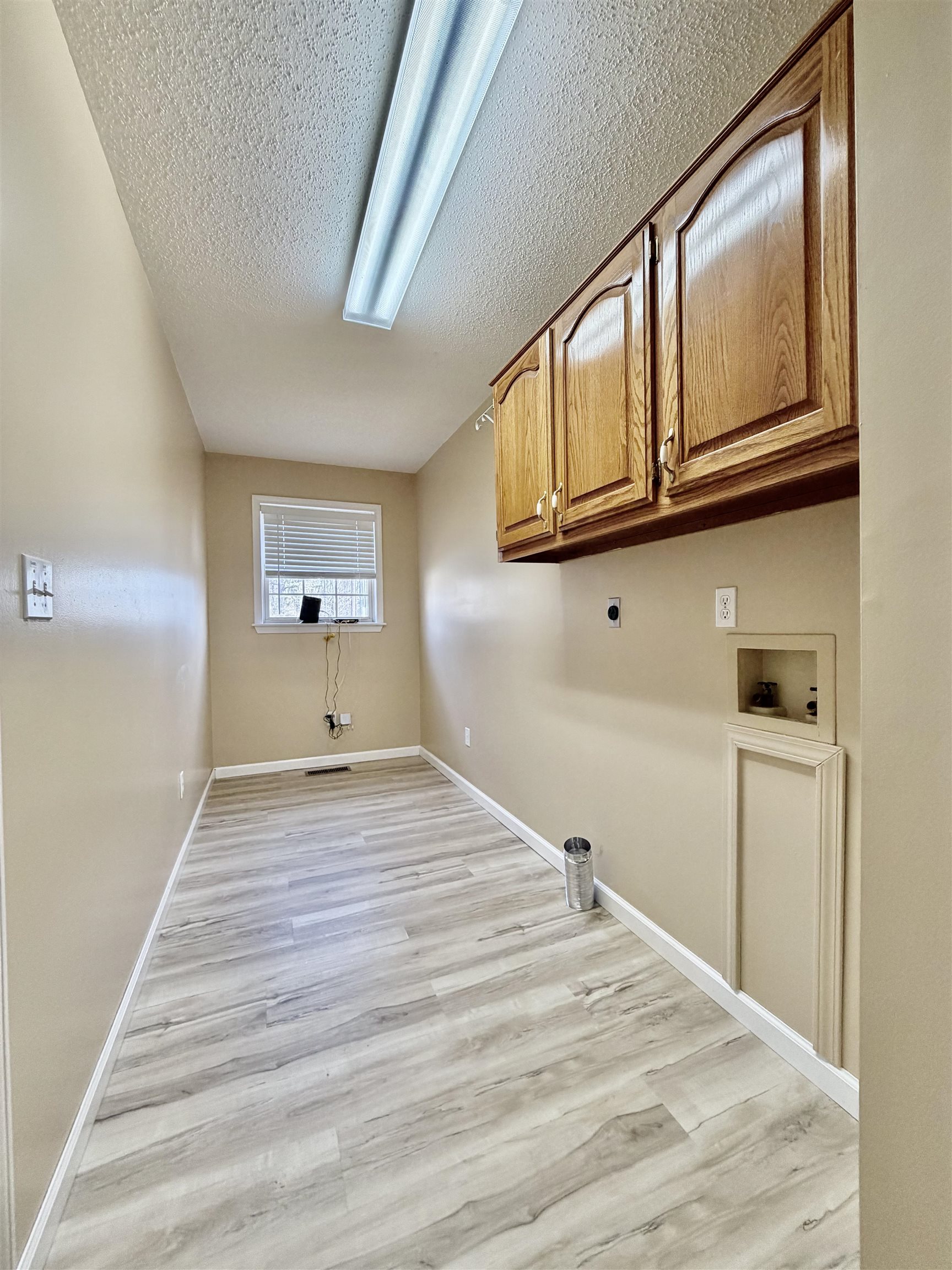 1086 Sloan Road Burlison, TN 38015 - Photo 24 of 24 Laundry room featuring cabinet space, light wood finished floors, a textured ceiling, washer hookup, and electric dryer hookup