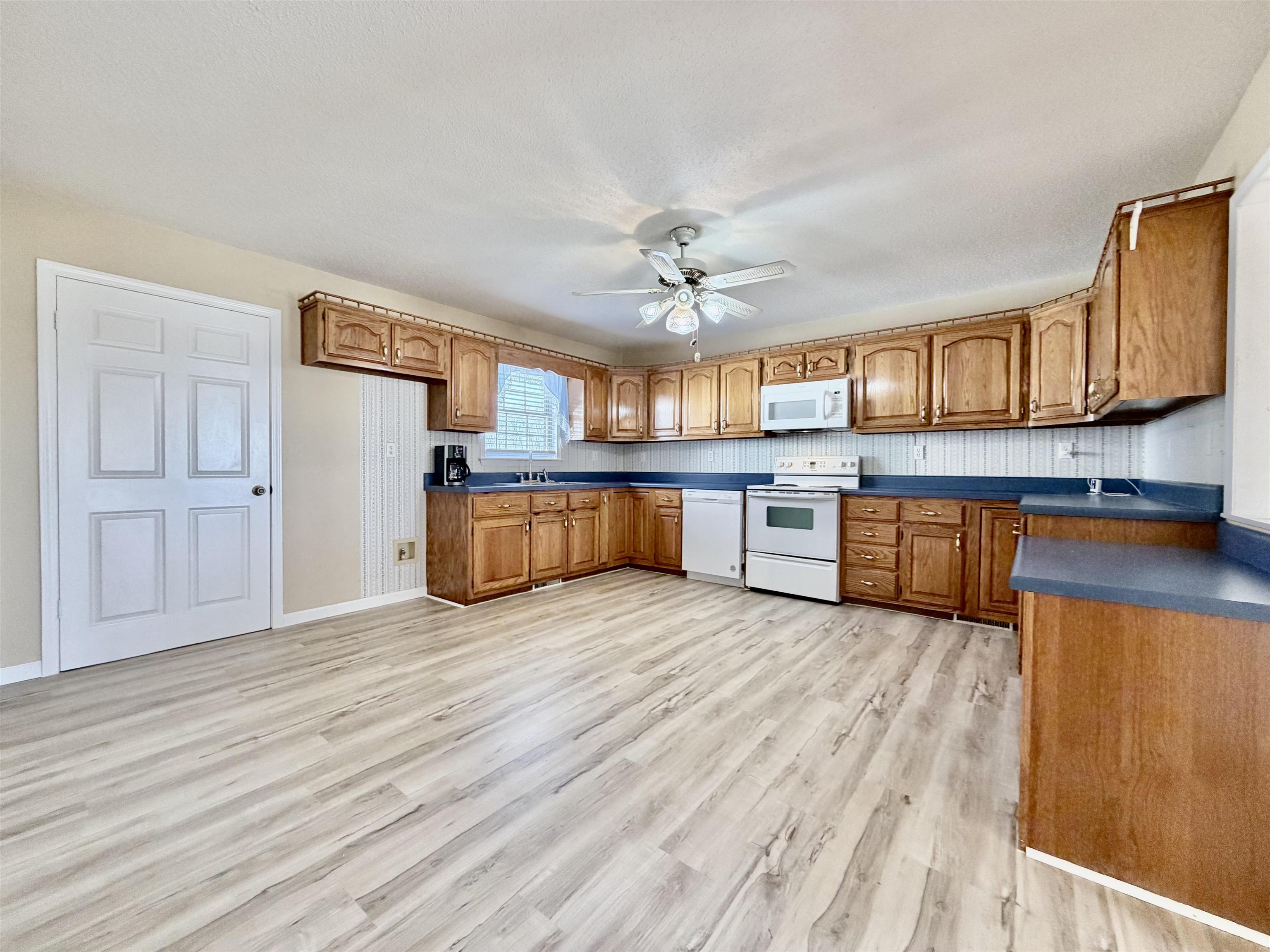 1086 Sloan Road Burlison, TN 38015 - Photo 7 of 24 Kitchen with dark countertops, wood finish cabinetry, white appliances, and a ceiling fan