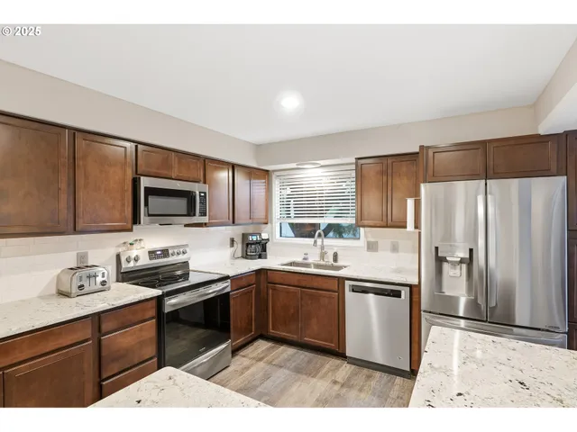 a kitchen with stainless steel appliances granite countertop a sink stove and refrigerator