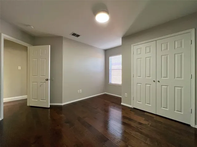 an empty room with wooden floor & windows and closet