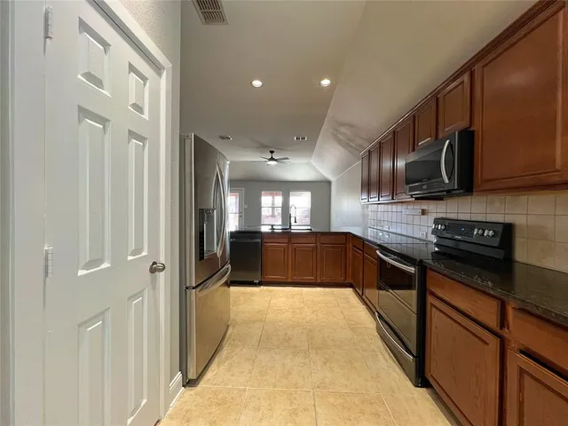 a large kitchen with stainless steel appliances granite countertop a large stove top oven a refrigerator and dishwasher