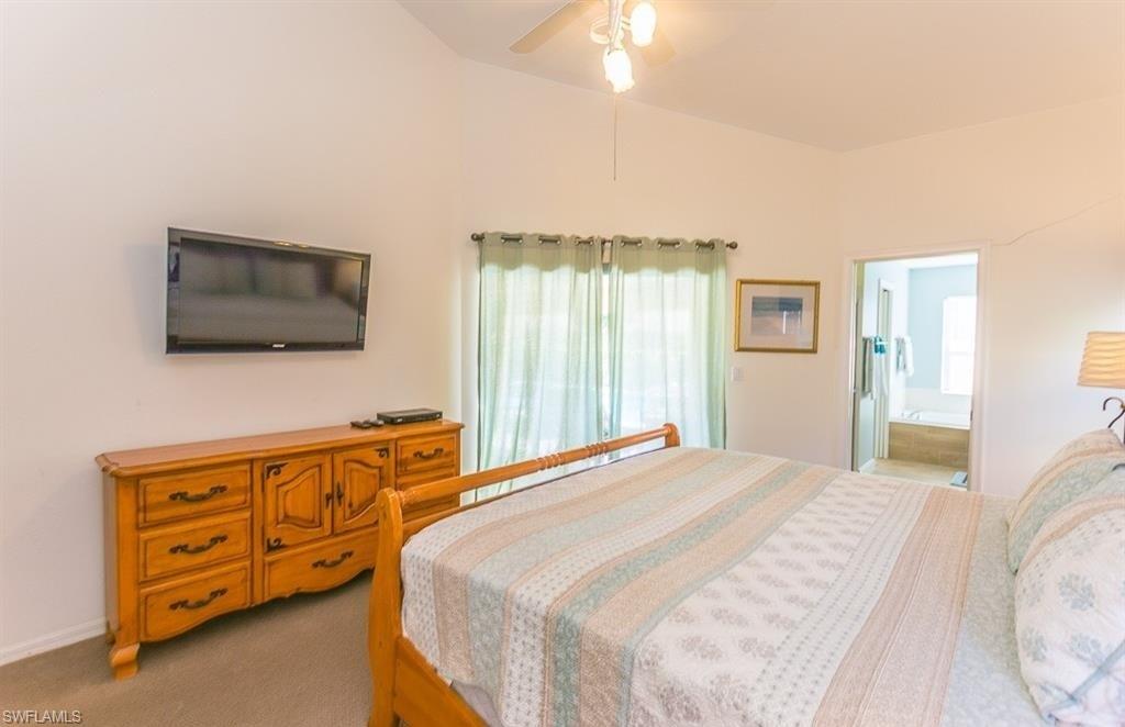 5077 Mabry Drive Naples, FL 34112 - Photo 12 of 24 a bedroom with a bed and a flat tv screen on dresser