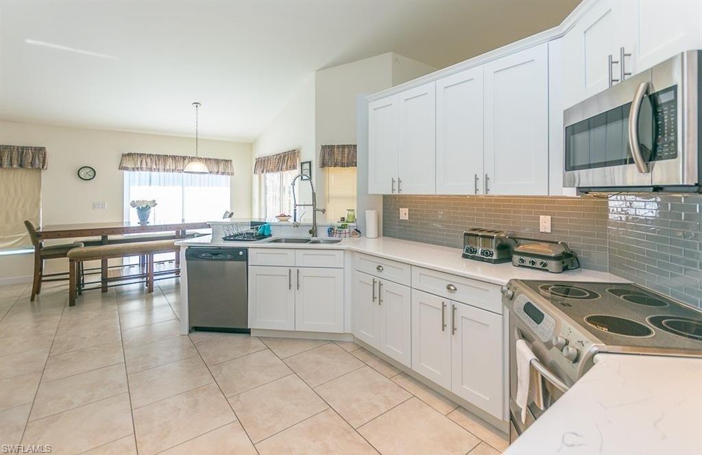 5077 Mabry Drive Naples, FL 34112 - Photo 9 of 24 a kitchen with a stove a sink and a microwave
