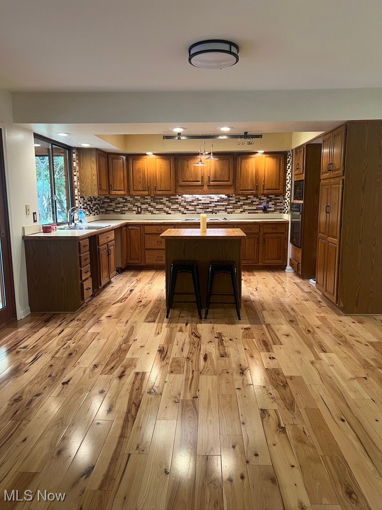 11331 Palmer Road Painesville, OH 44077 - Photo 13 of 47 Kitchen featuring light wood-type flooring, tasteful backsplash, a kitchen island, a kitchen breakfast bar, and stainless steel oven