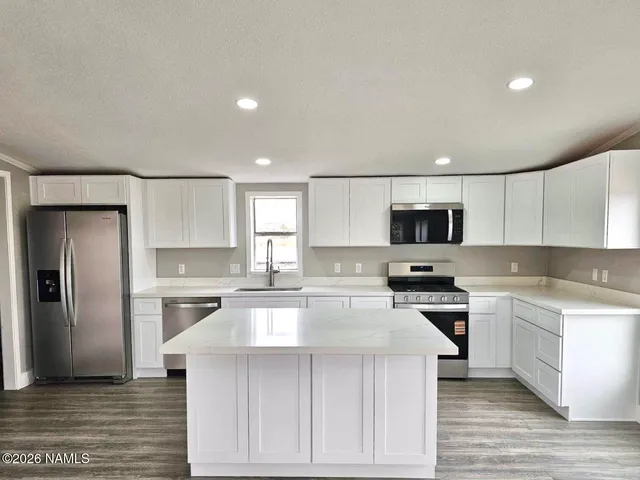 a kitchen with stainless steel appliances a stove a sink a refrigerator a microwave and cabinets