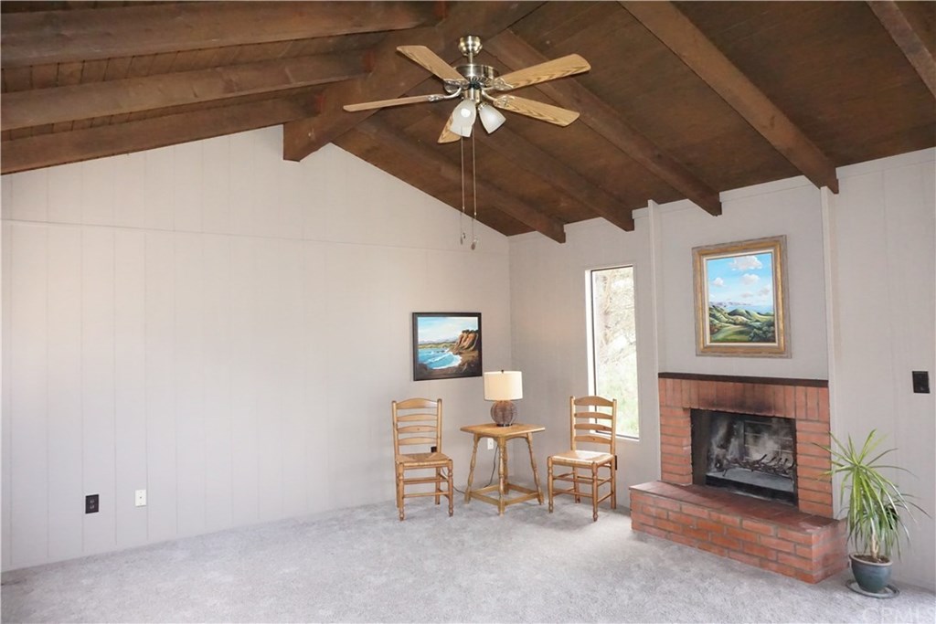 Living and dining areas with beam ceiling, fireplace, and views over Main Street and ocean.