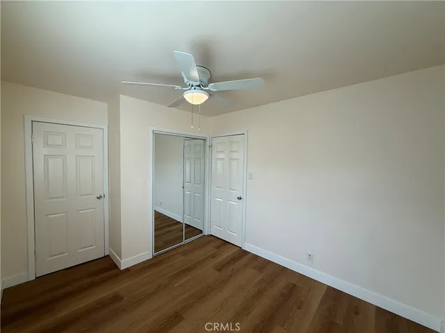 an empty room with wooden floor and ceiling fan